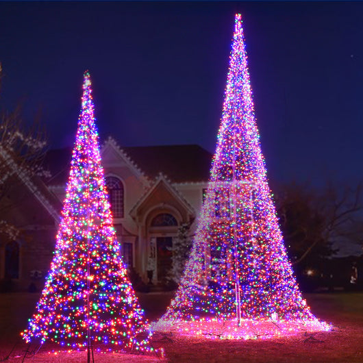 Two sizes of HOYECHI portable flagpole LED Christmas trees decorating a large front yard outdoor Christmas lighting display