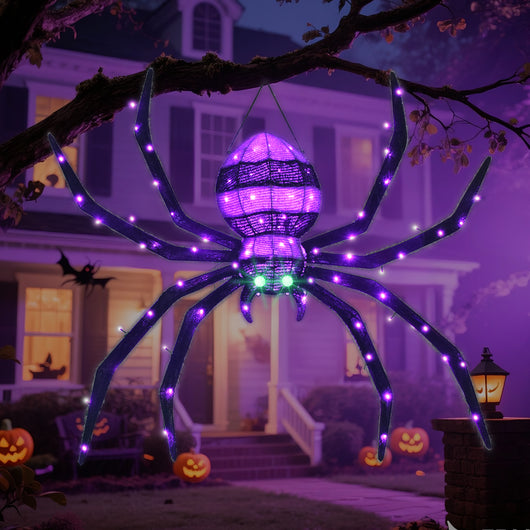 Large HOYECHI hanging Halloween spider glowing purple in spooky front yard with pumpkins and house in background