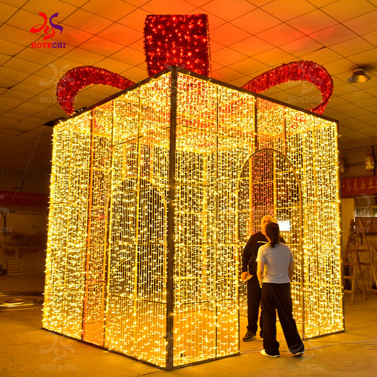 People standing inside HOYECHI walk-through LED gift arch showing scale of giant gift box entrance decoration