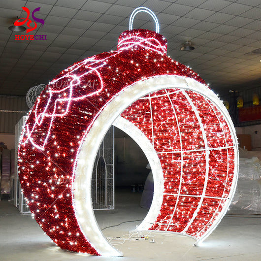 Side view of HOYECHI giant ornament arch steel frame wrapped with red tinsel and LED string lights creating a walk-through Christmas photo spot