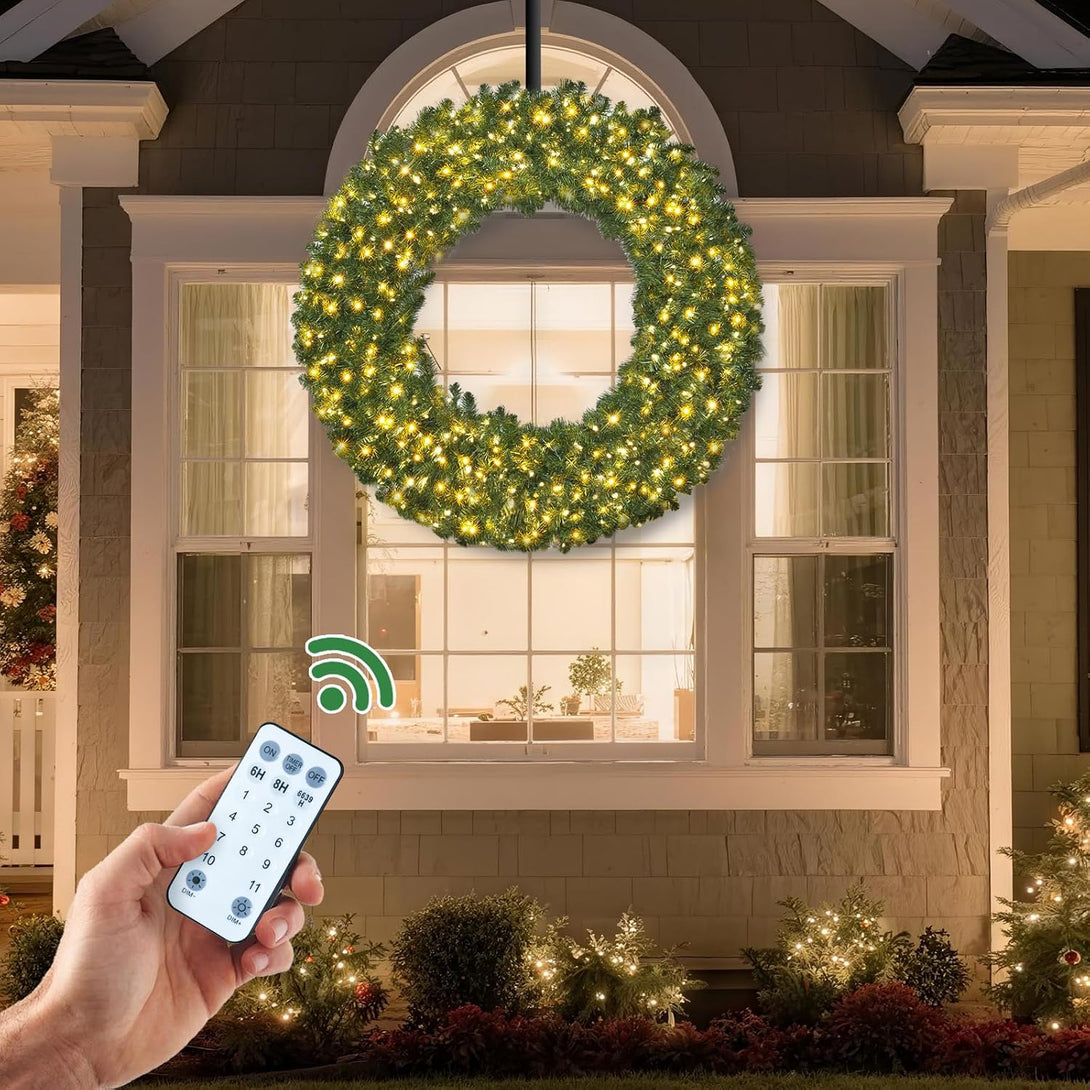 Scène promotionnelle officielle sur une fenêtre avec couronne verte, points lumineux d’aspect chaud, ouverture visible et main tenant une télécommande.