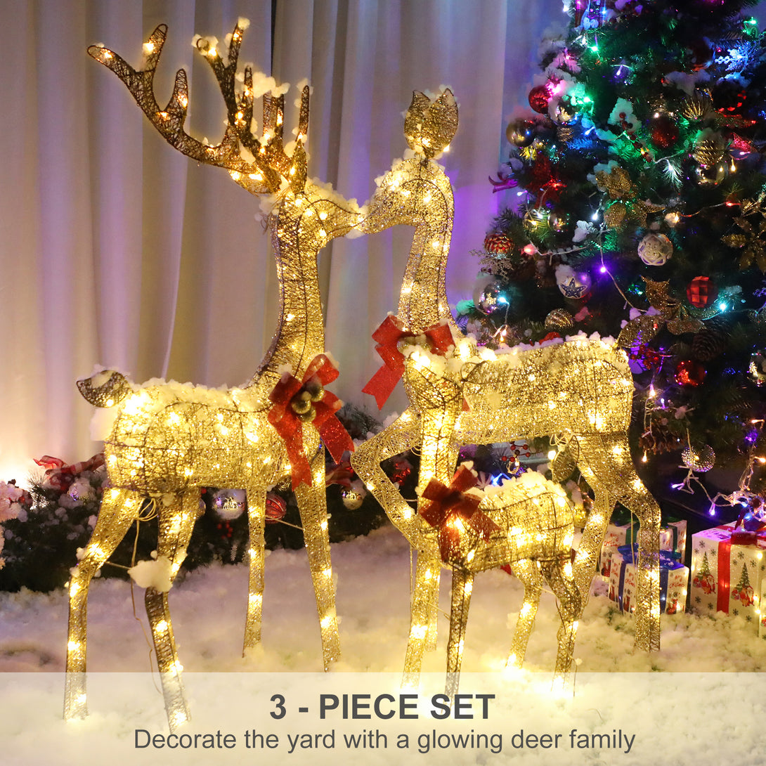 Familia de renos dorados iluminados junto a un árbol de Navidad decorado en una escena interior ambientada.